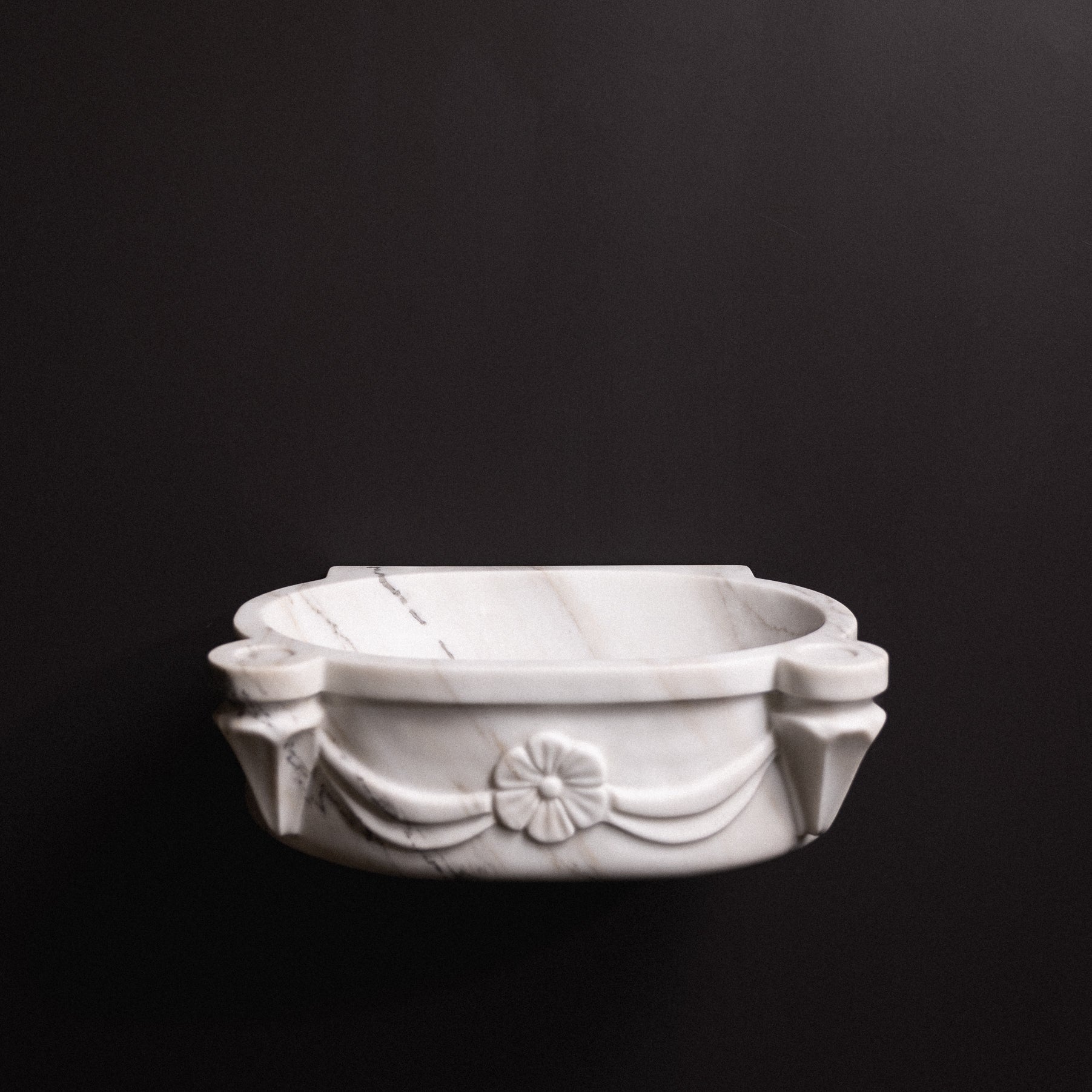 White marble floating wall-mounted sink with floral rosette carvings and draped detailing — luxury hand-carved marble basin for bathrooms.