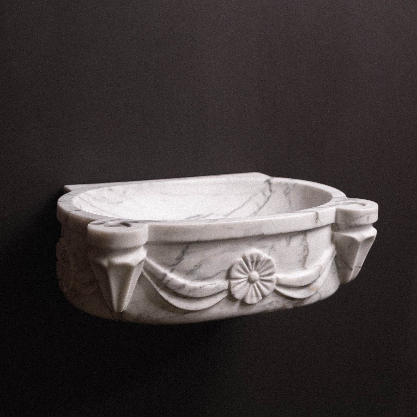 White marble floating wall-mounted sink with floral rosette carvings and draped detailing — luxury hand-carved marble basin for bathrooms.