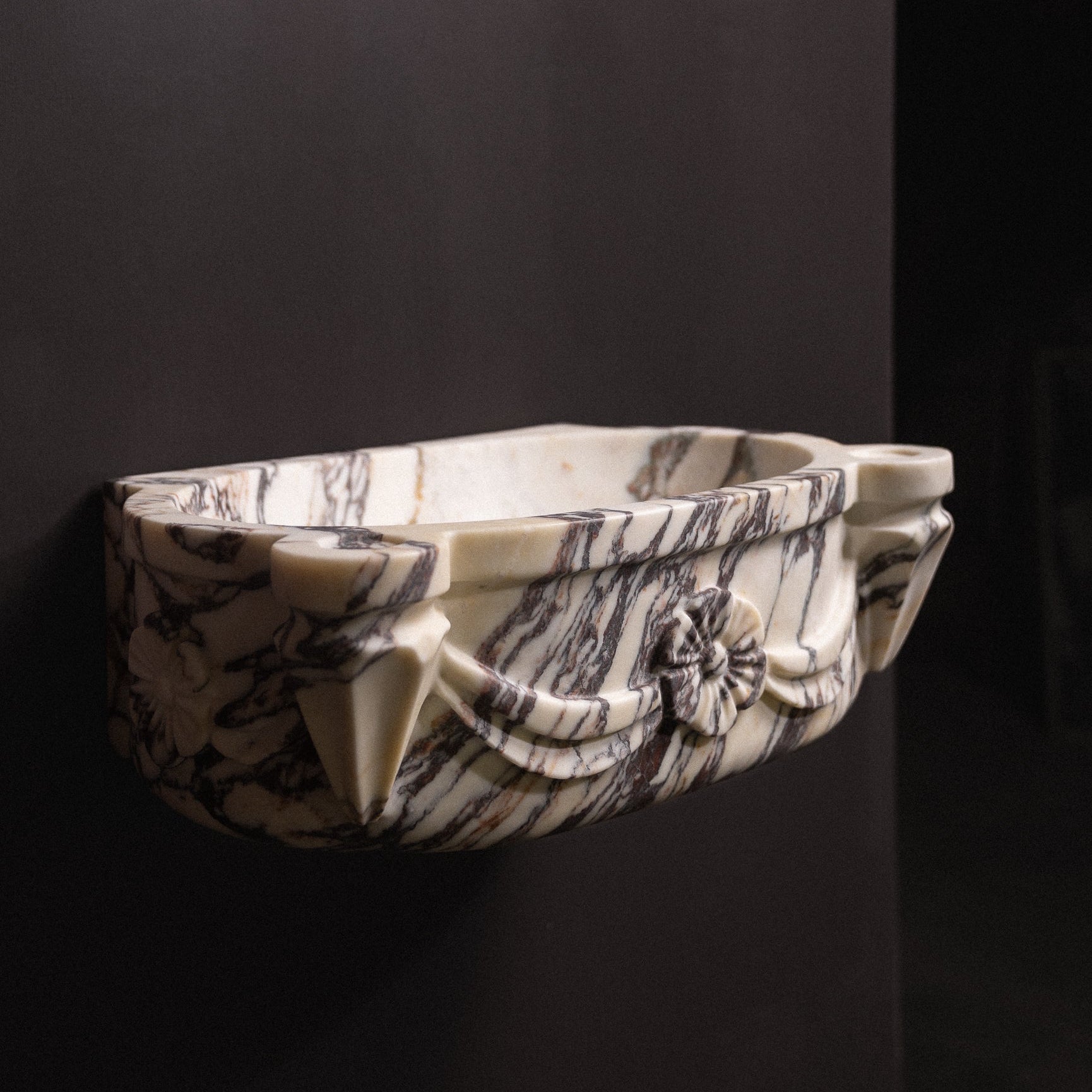 Calacatta viola marble floating wall-mounted sink with floral rosette carvings and draped detailing — luxury hand-carved marble basin for bathrooms.