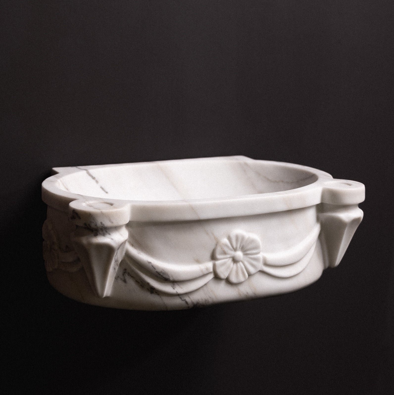 White marble wall-mounted sink with floral rosette carvings and draped detailing — luxury hand-carved marble basin for bathrooms.