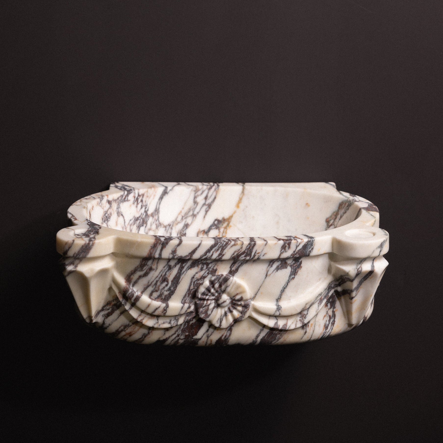 Calacatta viola marble floating wall-mounted sink with floral rosette carvings and draped detailing — luxury hand-carved marble basin for bathrooms.